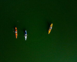 Aerial photograph, taken with a drone, looking down on three kayakers as they paddle across the...