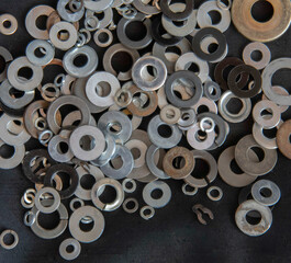 Fototapeta premium Closeup of an assortment of steel and brass washers of different sizes and types laying on a black background,