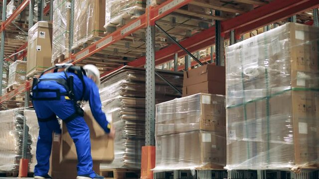 Engineer wearing exoskeleton, exosuit. Warehouse worker in exoskeleton is putting boxes together. Exoskeleton, exosuit, robotic technology concept.