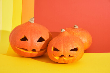 three jack lantern from pumpkin on colored geometric background, copy space, halloween decoration concept