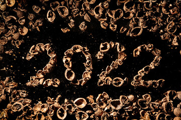 2022 new year. Numbers made from a pile of nutshells. Food style calendar. Wallpaper. Banner. Brown color walnut texture. Signed two and zero. Flat lay mockup design. Business card. Black background