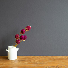 Vase of purple globe amaranth flowers on wooden table. gray wall background. copy space