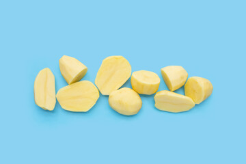 Raw peeled potatoes on blue background