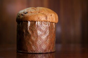 Panettone on the wooden table with textured brown woody background. Panettone concept. Space for...
