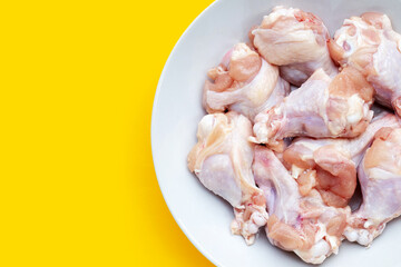 Fresh raw chicken wings (wingstick) in white plate on yellow background.