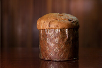 Panettone on the wooden table with textured brown woody background. Panettone concept. Space for text. Christmas concept.

