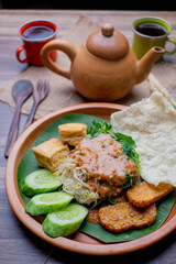 Nasi Pecel and two cups of tea as background. Nasi Pecel is Indonesian traditional food, rice dish of steamed rice with vegetables salad, peanut dressing, tempeh, beancurd and crackers