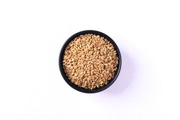 Wheat grain in a black bowl on white background, Top view