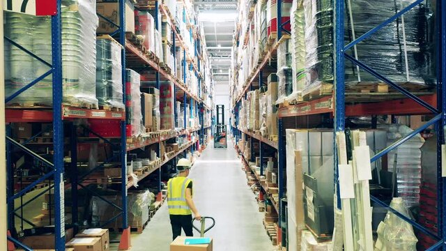 Warehouse passage with a male employee pulling a trolley