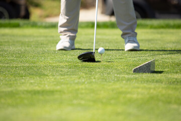 A view of a golfer preparing to swing his club at a golf ball resting on a tee.