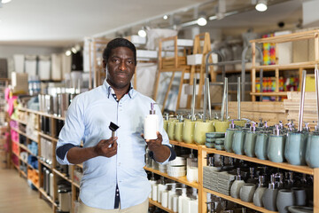 Interested african american man visiting store of household goods in search of new bathroom...