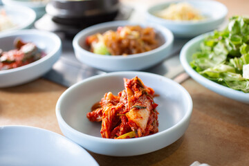A view of a plate of kimchi, part of an array of small side dishes known as banchan, seen in a Korean BBQ restaurant.