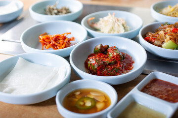 A view of several varieties of banchan, delicious side dishes that you eat with cooked meat slices in a Korean BBQ restaurant.