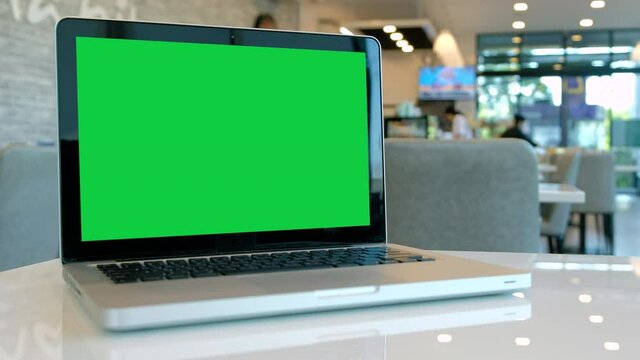 Chroma key green screen laptop computer set up for work on a cafe desk.	