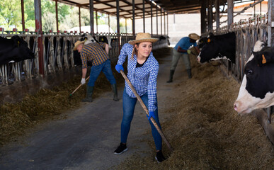 Portrait of active female employee working in cowshed on farm