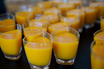 A closeup view of several shot glasses of Indian mango lassi drinks