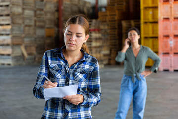 European female employee with papers working at the warehouse