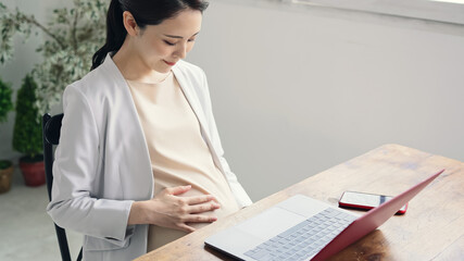 部屋でパソコンを使う妊婦