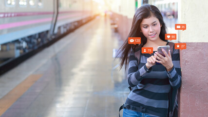 Happy and beautiful asian woman standing in train station use mobile phone with social media...