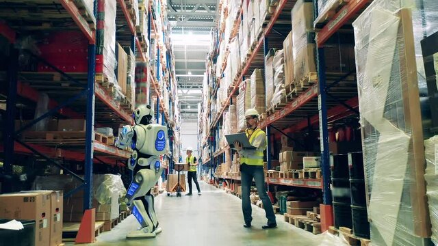 Engineer is operating a robot in the storage