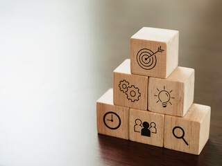 Modern business icons on wooden cube blocks, pyramid steps on desk with copy space. Leadership, key...