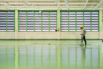 Construction worker using floor grinding machine polishing floor before epoxy primer Self-leveling...
