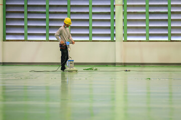Construction worker using floor grinding machine polishing floor before epoxy primer Self-leveling...