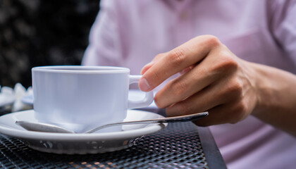 man's hand taking a white cup of coffee, he finds himself having breakfast outdoors