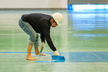 Construction worker using trowel spreading epoxy putty for Self-leveling method of epoxy floor...