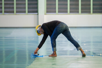Construction worker using trowel spreading epoxy putty for Self-leveling method of epoxy floor...