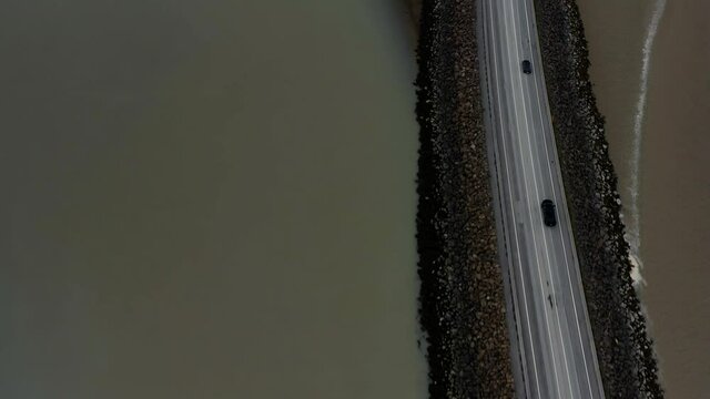 Vehicles Driving On The Road Between Shallow Murky River In Westfjord, Iceland. - aerial
