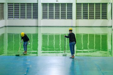 Construction workers are using rollor spreading green epoxy coating floor for Self-leveling method of epoxy floor finishing work