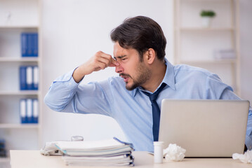 Young male employee suffering at workplace