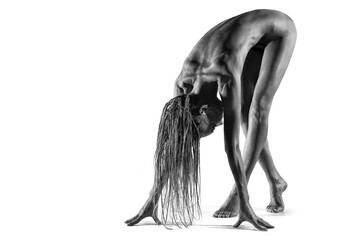 Obraz na płótnie Canvas Beautiful nude sexy fitness girl with great figure and dreadlocks flexing her perfect body in a yoga pose over white
