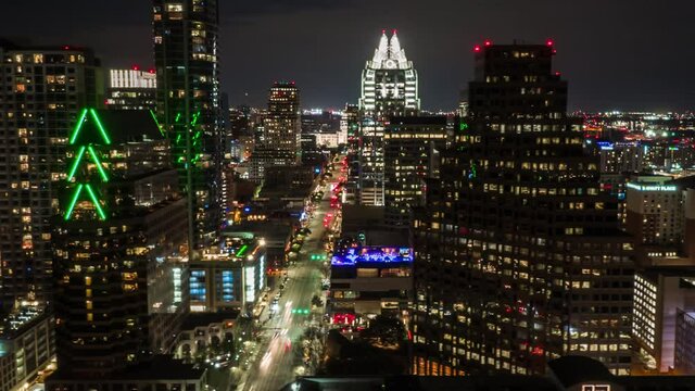 Aerial Hyperlapse of Downtown Austin at night revealing Capitol building over Congress Avenue with city traffic and tall buildings passing by.