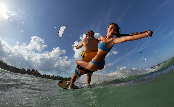 Lovely couple up on one kite board. Woman Riding On Kite surfer's Back and kiting on a sea