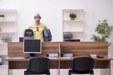 Young male employee preparing for trip at workplace