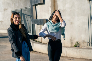 Two beautiful happy smiling women walking through an urban setting. Joy concept.