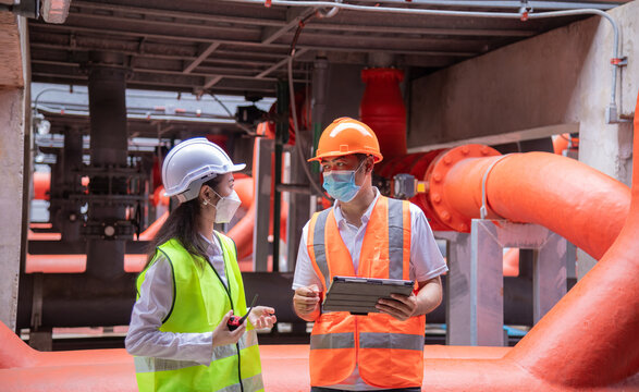 Engineer Under Checking The Industry Cooling Tower Air Conditioner Is Water Cooling Tower Air Chiller HVAC Of Large Industrial Building To Control Air System ,wearing Mask For Protect Pollution.