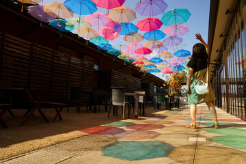 氷見一番街のテラスで青空を彩るたくさんのビニール傘と鮮やかな傘の影に一人の女性