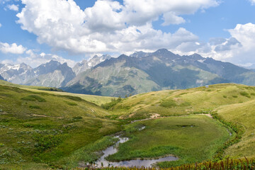 Obraz premium Summer mountain landscape in Svaneti region, Georgia, Asia. Snowcapped mountains in the background. Blue sky with clouds above. Georgian travel destination
