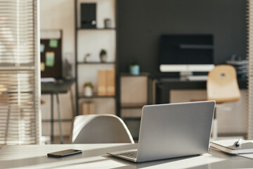 Background image of minimal home office desk lit by sunlight with focus on opened laptop, copy space