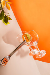 Two empty glasses and a fork levitate on a orange background with copy space.Image of a levitating drinking glasses.Trendy concept geometric image.Zero gravity or levitation conception.