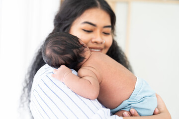 Newborn baby or infant sleeping on mother shoulder. Happy African American mum holding comforting...