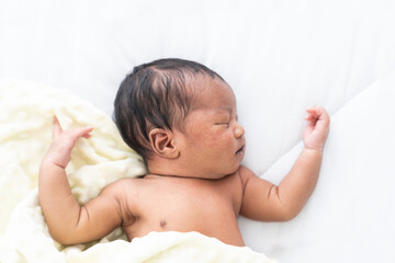 Top view of Newborn baby sleeping with blanket on white bed. Infant lying on white bed. African...