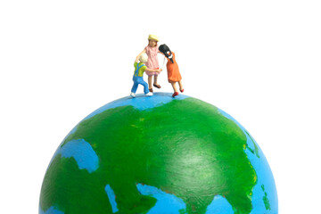 Miniature people toy figure photography. International kids day concept. A group of kids playing above earth globe, isolated on white background