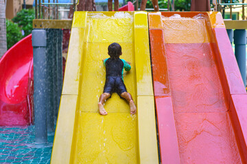 Happy boy or child in sliding down the water park ride during warm summer day