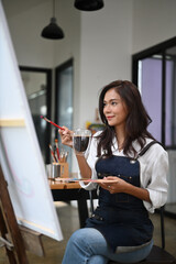 Beautiful creative woman drinking coffee while sitting at her art workshop.