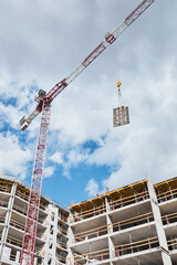 Vertical low angle shot of residential building under construction with construction crane against blue sky, copy space