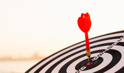 Dart arrow hit to center on bullseye(bull's-eye) of a dartboard is a target of purpose challenge business at sunset, expert strategy market target, objective financial and goal a concept